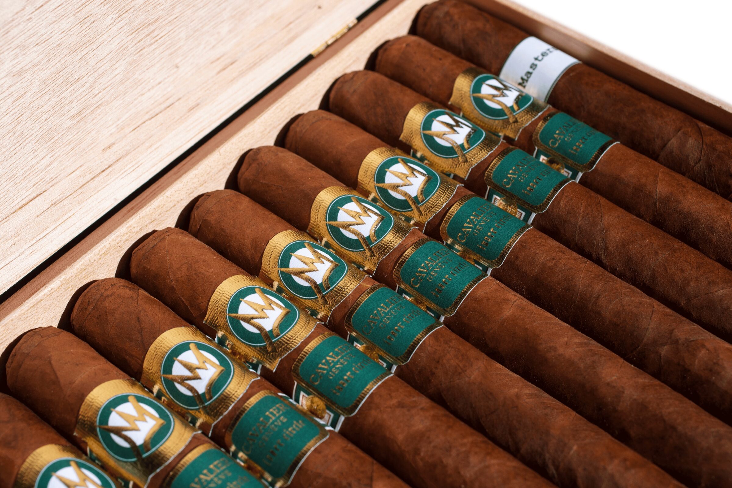 Cavalier Genève The Green Jacket 2025 Churchill cigars arranged in wooden cigar box showing Honduran Claro wrappers and gold crown bands