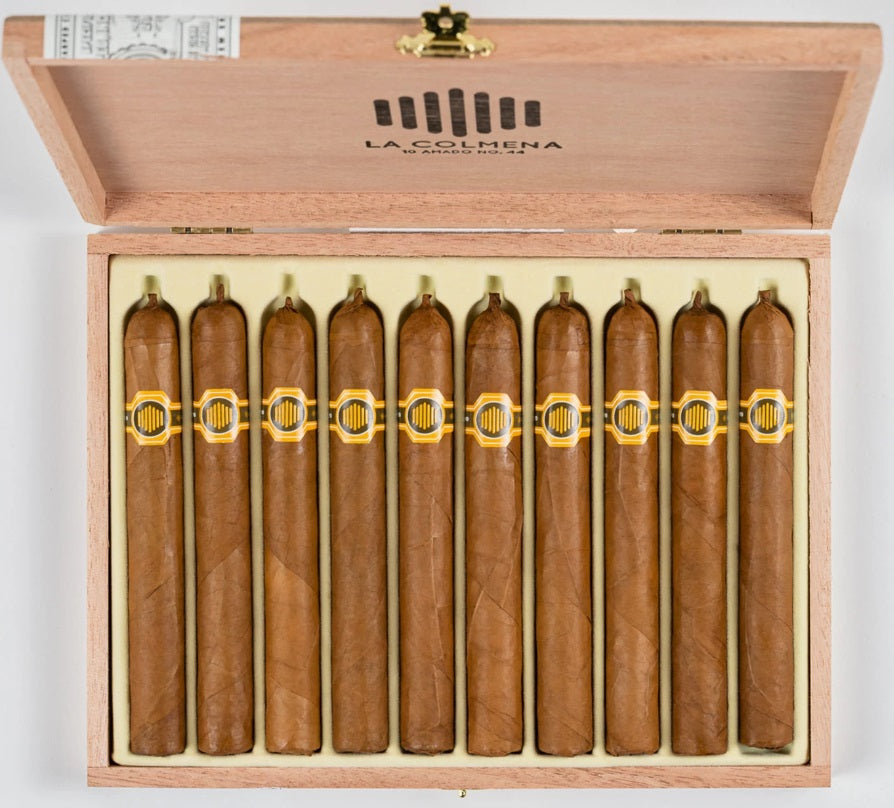 Warped La Colmena cigar resting on box lid, showing natural wrapper and elegant gold label.